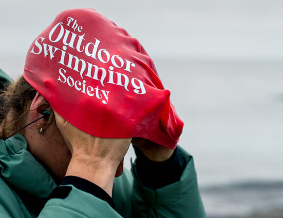 swimmer putting a red oss swim cap on their head
