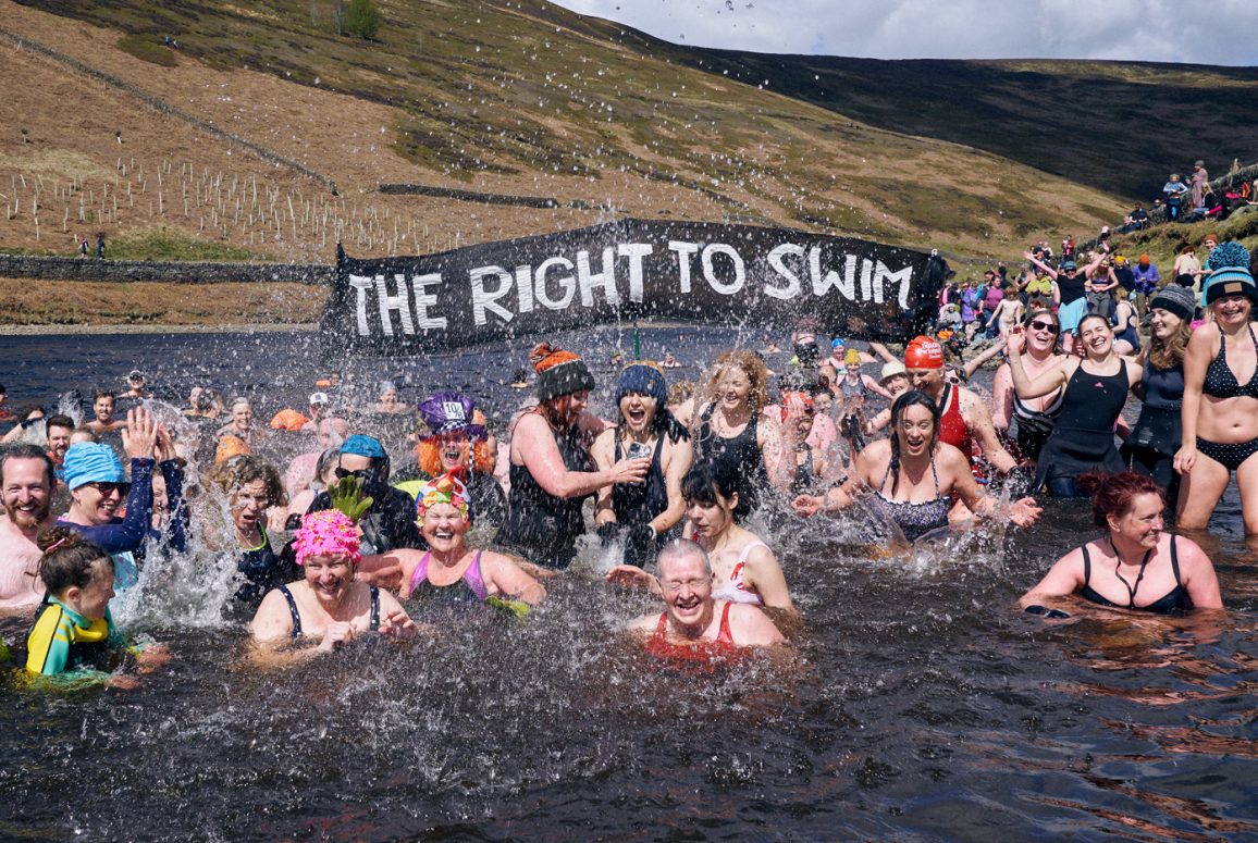 many swimmers and Right to Swim banner in a reservoir