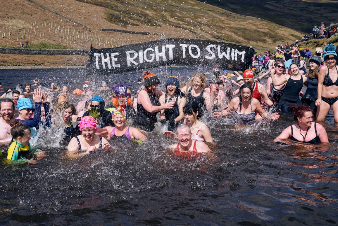 many swimmers and Right to Swim banner in a reservoir