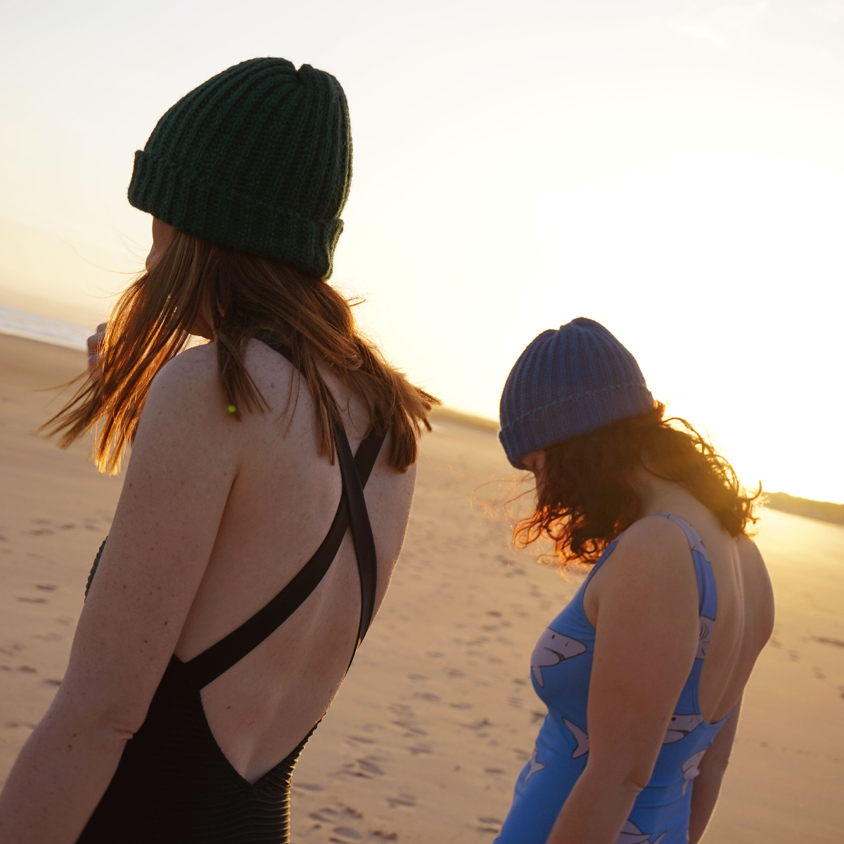 two swimmers on beach wearing beanie hats