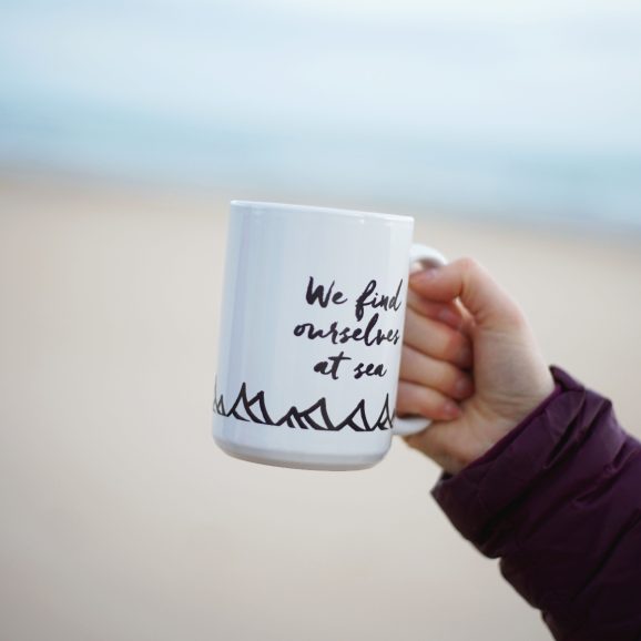 OSS mug being held on beach