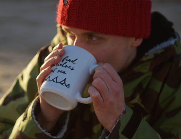 man in red beanie hat drinking from OSS mug