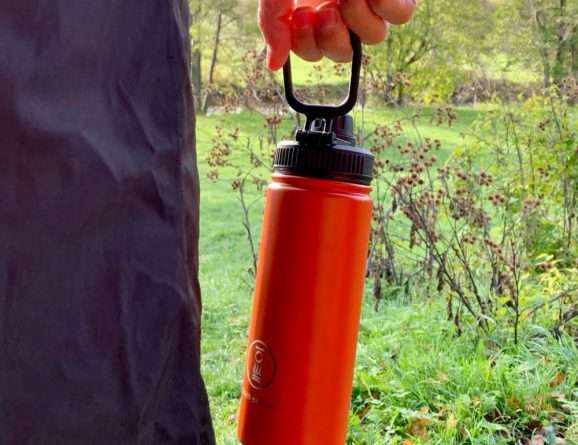 orange flask being held by its fold out handle