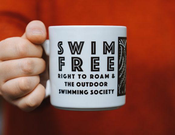 Person holding a Swim Free mug with the Swim Free text visible