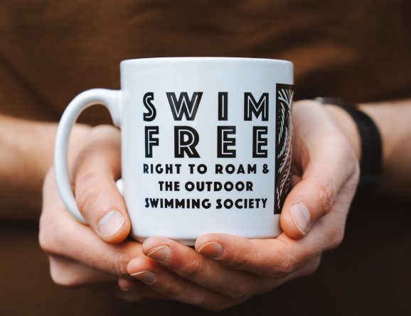 Person holding a Swim Free mug with the Swim Free text visible