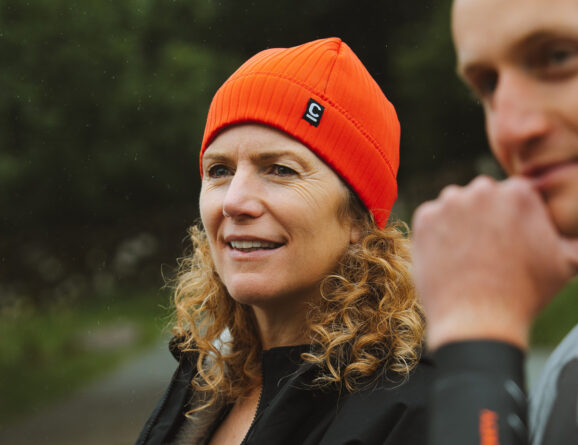 Front view of a woman wearing a red storm chaser beanie