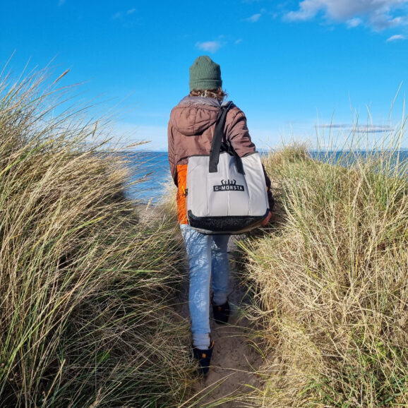 Woman walking through dunes carrying a mini split bag over her shoulder