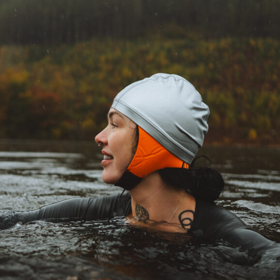 Woman in a silver swimming cap with a neoprene bonnet underneath