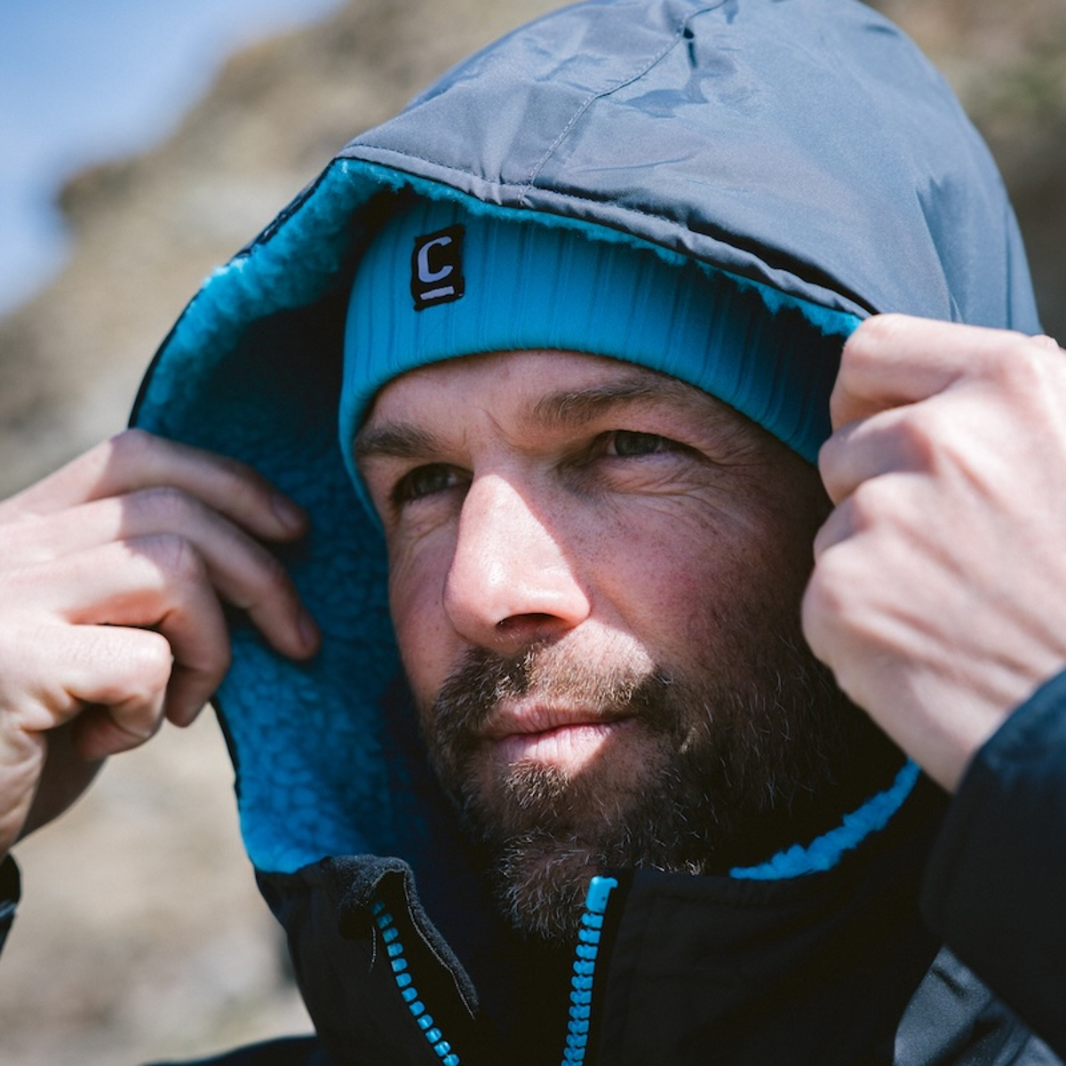 CJB Surf/C-Skins Man wearing a storm chaser beanie in teal with his hood over the top